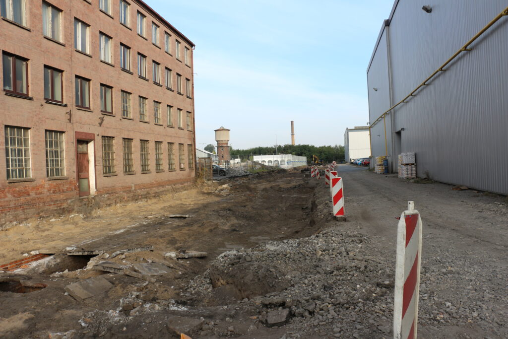 Budowa drogi przez Dozamet - dalsza część budowanej drogi po obu stronach stare hale produkcyjne