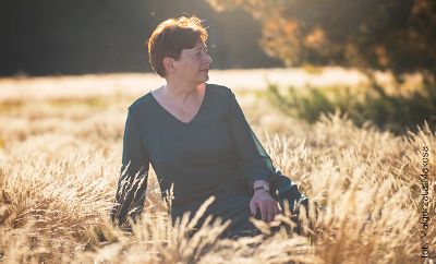 Na zdjęciu pisarka Zofia Mąkosa która siedzi na trawie. Jest słoneczna, jesienna pogoda