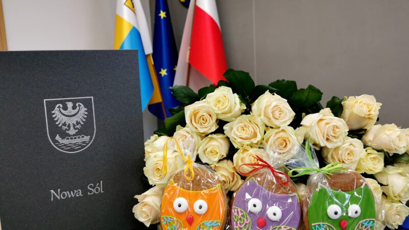 Na zdjęciu białe róże, kolorowe pierniczki w kształcie sówek oraz okładka dyplomu