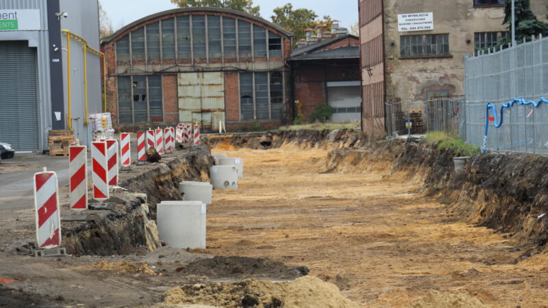 prace przy budowie drogi przez Dozamet - wykopany dół w tle dawne hale zakładu