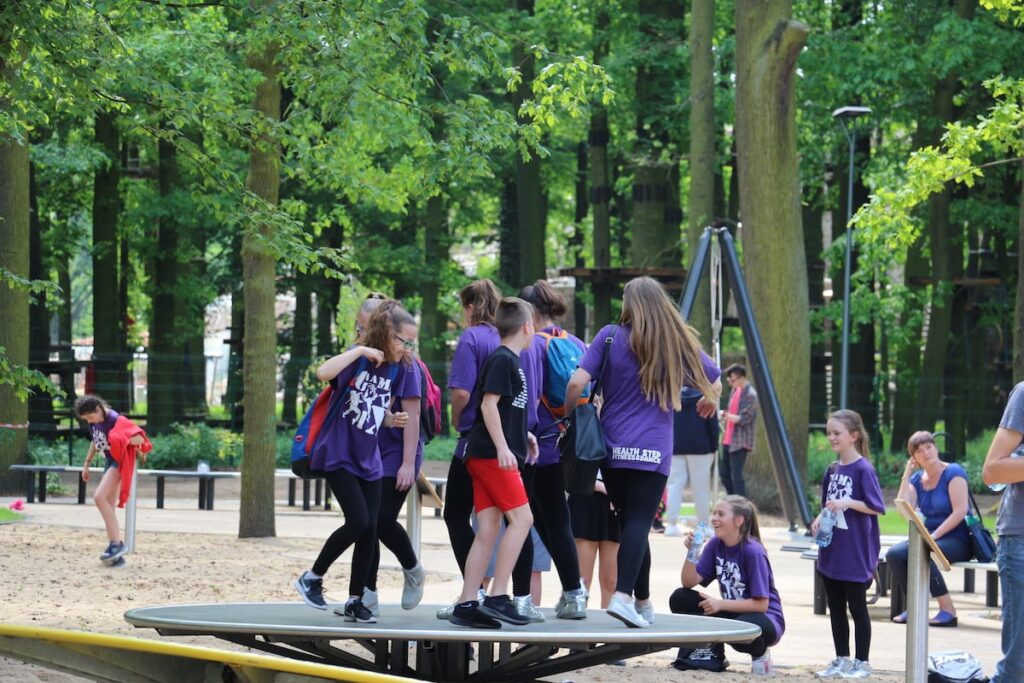 Grupa dzieci w wieku szkolnym korzysta z jednej z atrakcji w parku fizyki