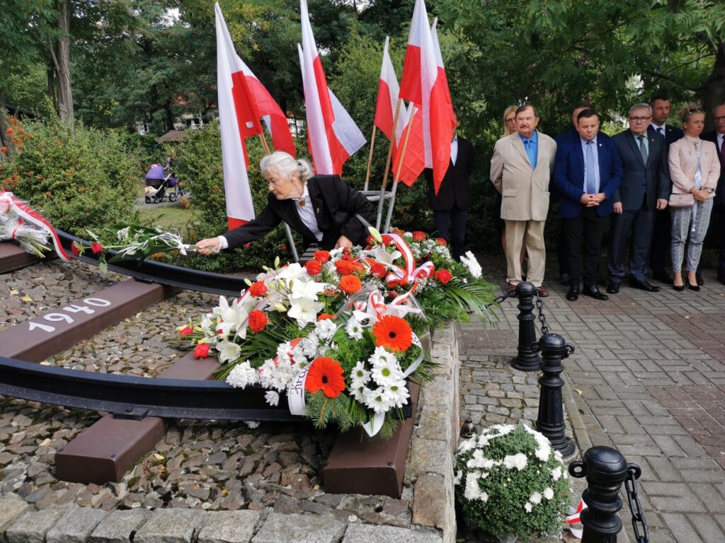 Danuta Cygan składa kwiaty przed pomnikiem Sybiraka. W tle pozostali uczestnicy uroczystości