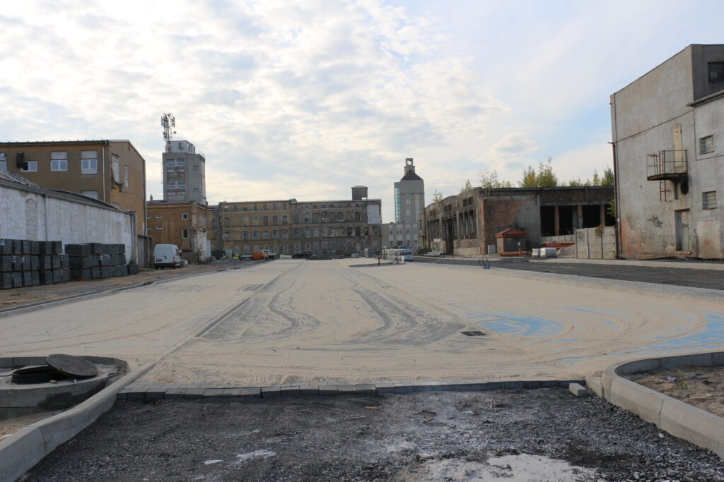Na zdjęciu znajduje się budowany parking wraz z drogą na terenie dawnego zakłądu NFN Odra. W tle budowana wieża zegarowa