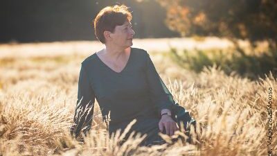 Na zdjęciu pisarka Zofia Mąkosa która siedzi na trawie. Jest słoneczna, jesienna pogoda