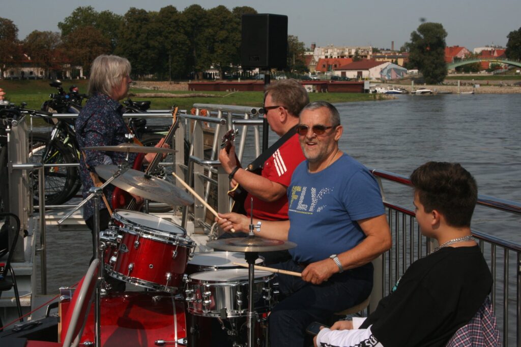 Na zdjęciu znajdują się muzycy uczestniczący w rejsie laguną. Na pierwszym planie perkusista, za nim dwóch gitarzystów