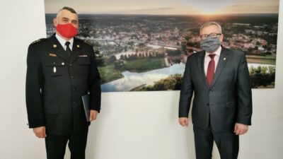 Na zdjęciu od lewej komendant Tomasz Duber oraz prezydent Jacek Milewski. Panowie stoją w dystansie od siebie na twarzy mają maseczki zasłaniające usta i nos
